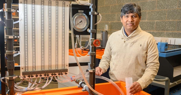 This is a portrait of Dr. Jagadish Torlapati, a man with short black hair streaked with gray, standing in a lab.