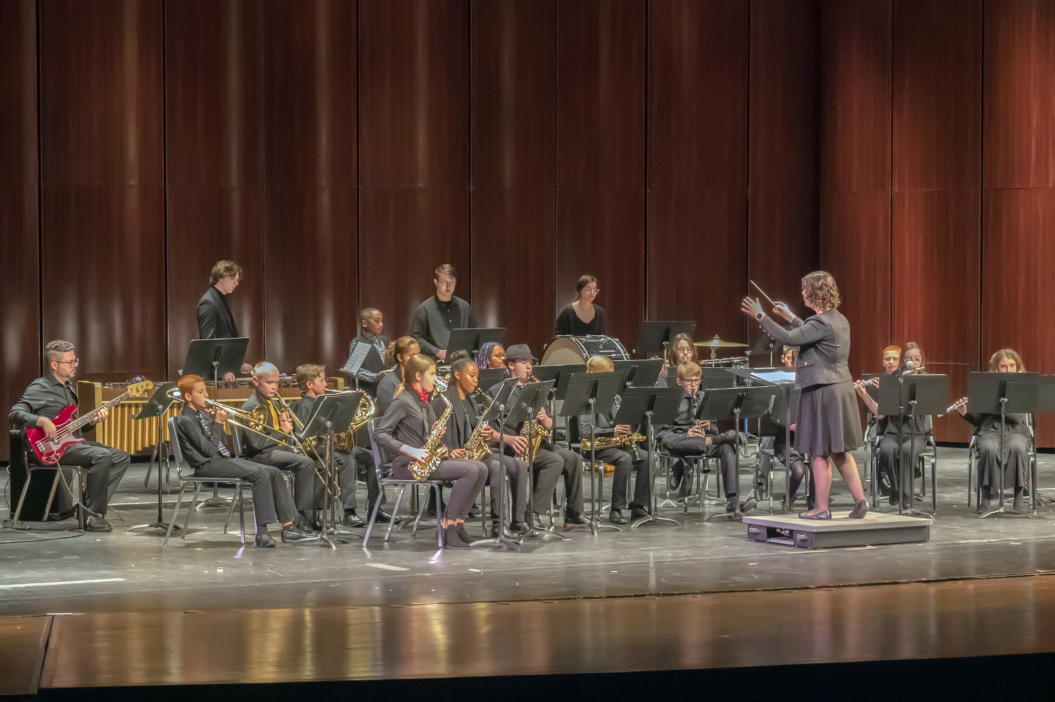students playing wind instruments on stage led by faculty instructor