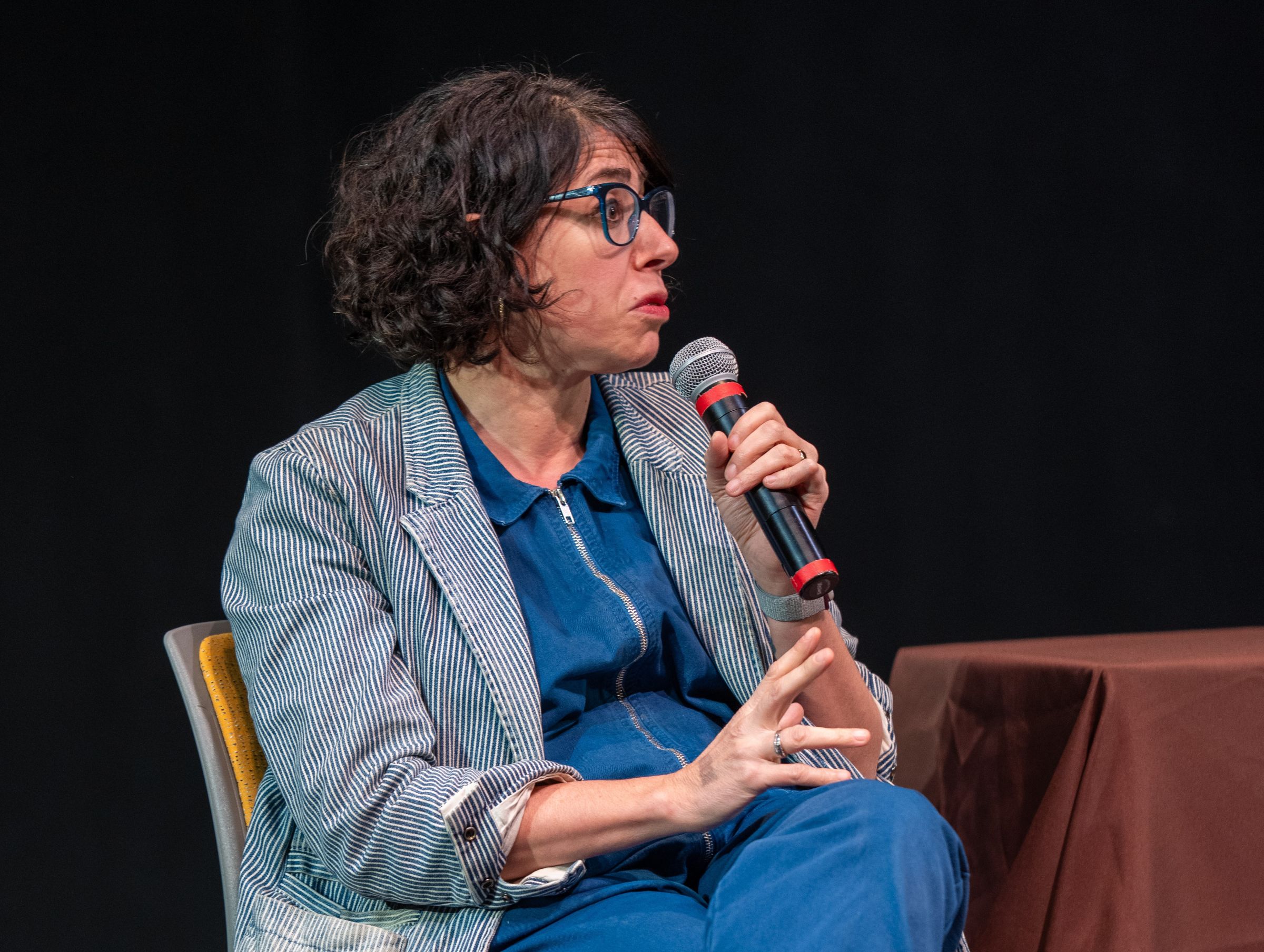 Rachel Chavkin speaks into microphone during a conversation with theatre students