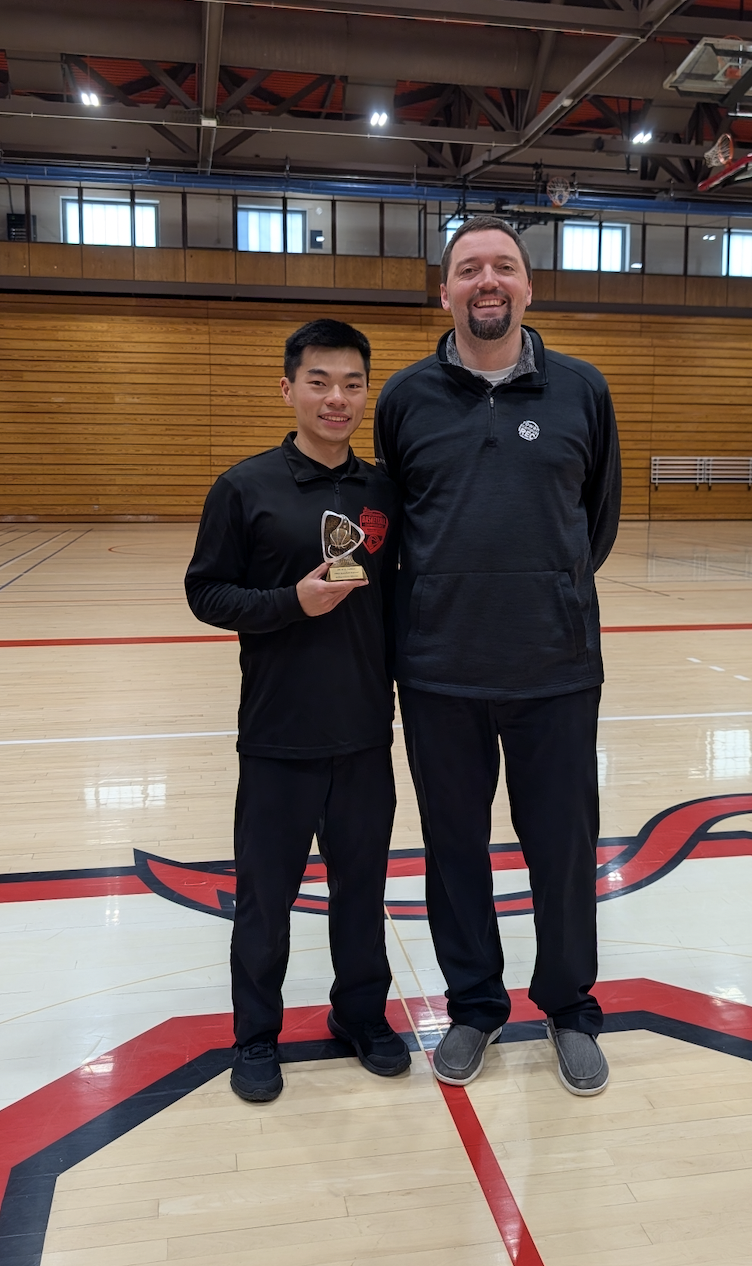 Student official stands with staff mentor after winning tournament