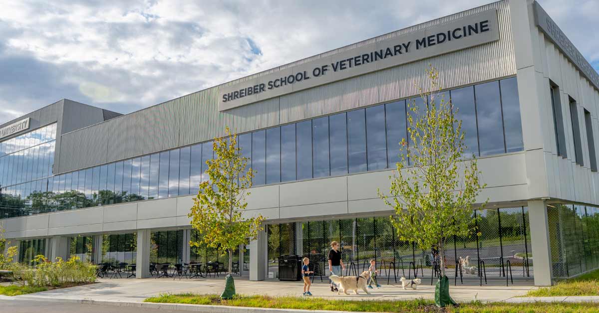 A family walks their dog outside of Shreiber School of Veterinary Medicine.